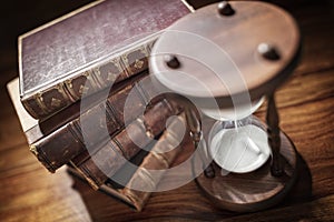 Hourglass and old books in library