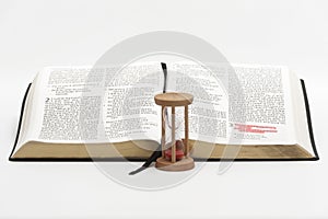 Hourglass and open bible on the book of Ecclesiastes with selective focus on verse 1 of chapter 3 highlighted in red