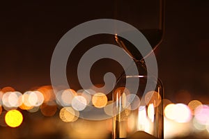 Hourglass over bokeh city lights as time passing concept for business deadline.