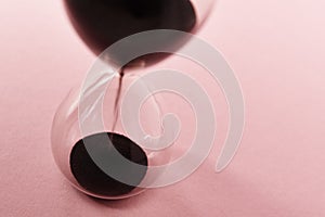 Hourglass on pink background, closeup. Urgency and running out of time concept