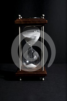 Hourglass, or sand clock isolated in black background, in low li