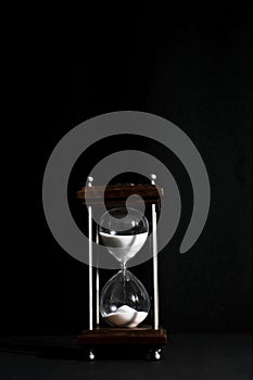 Hourglass, or sand clock isolated in black background, in low li