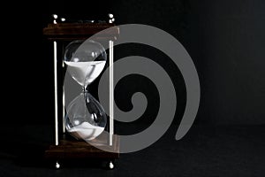 Hourglass, or sand clock isolated in black background, in low li