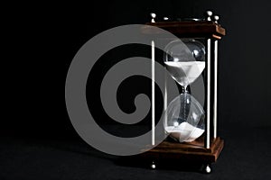 Hourglass, or sand clock isolated in black background, in low li