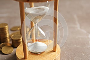 Hourglass with sand and coins on table. Time management