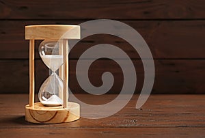 Hourglass with sand on table against dark background. Time management