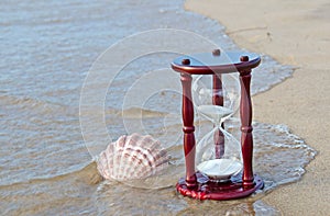 Hourglass with seashell on seashore