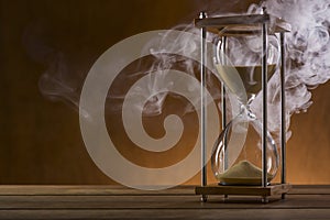 Hourglass and smoke on a wooden table