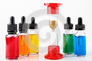 Hourglass started the countdown and transparent glass bottles filled colored liquid with dropper