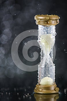 Hourglass under the water drops isolated on black background. Time limited. Deadline. Marketing strategy.