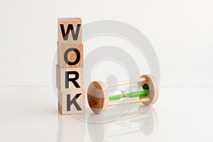 Hourglass and wood blocks with text WORK on bright white background. Business, career, waste of time, procrastination concept