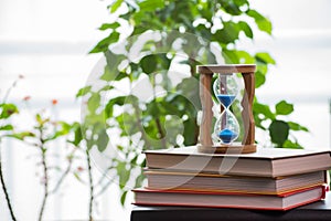 Hourglasses and book on a wooden table.