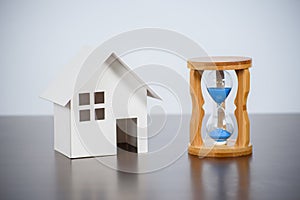 Hourglasses with model house on a wooden table.