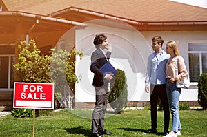 House agent showing new property to potential buyers, outside. Blank space