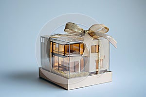 House as a gift. House architectural model in a gift box with a bow. Buying a new home, inherit real estate. Mortgage and home