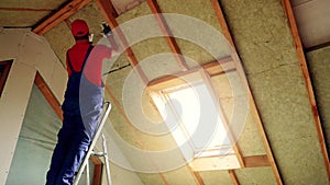 house attic insulation - construction worker installing rock wool in mansard wall