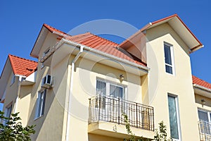 House with attic, metal roof and roof gutter outdoor. Home Guttering, balcony,  roof gutters, plastic guttering system exterior