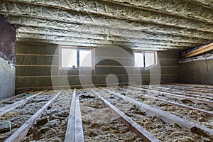 House attic under construction. Mansard walls and ceiling insulation with rock wool. Fiberglass insulation material in wooden fram