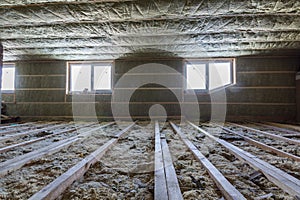 House attic under construction. Mansard walls and ceiling insulation with rock wool. Fiberglass insulation material in wooden fram