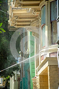 House being hosed or cleaned in the front yard with dusty facade and visible exterior windows and white accent beams in