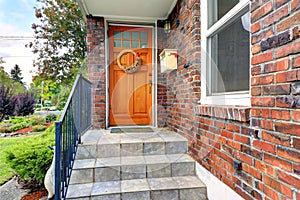 House with brick trim. Entrance porch with orange door