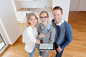 House broker and clients in new apartment looking into camera