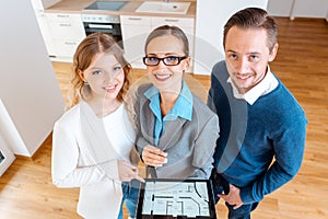 House broker and clients in new apartment looking into camera