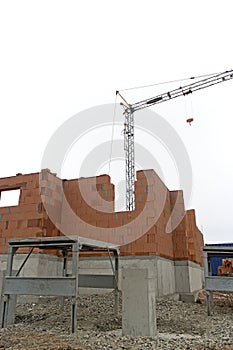 House building construction site with brick walls and a building crane