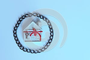 House in chains. A small white house is decorated with a decorative key on a red ribbon.