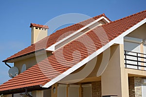 House with clay tile roof, rain gutter, chimney, gable and valley type of roof construction. Building attic house construction wit photo