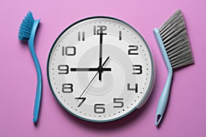 House cleaning product on pink table background, clean time with cleaning tools and clock