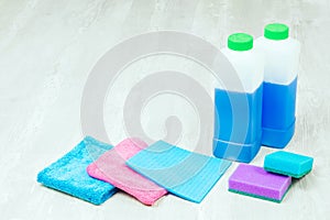 House cleaning supplies close up on wooden background. Rags and bottles.