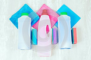 House cleaning supplies close up on wooden background. Rags and bottles.