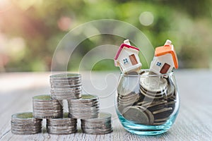 A house on a coin in a glass bottle The coins are stacked into triangular bases. A natural green background that saves money and