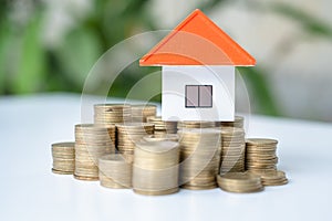 House and coins in the hands of investors.Orange roof house.Save money for buying a new home and borrowing money to plan the real