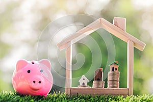 House on the coins placed in a model house and a Piggy bank on the grass. planning savings money of coins to buy a home