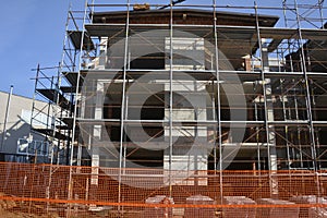 House construction scaffolding with orange mesh and blue sky