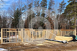 House construction site with wall studs and stacks of wood lumber