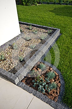 House corner design idea: stone framing as flowerbed, evergreens and lavender plants, terrace