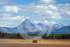 House in the countryside with the mountains in the background. Farm cabin in the rural country surrounded by forest and hills with