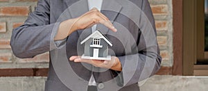 The house is covered by the hands of a real estate agent to protect the house for customers, homebuyers, insurance, ready give to