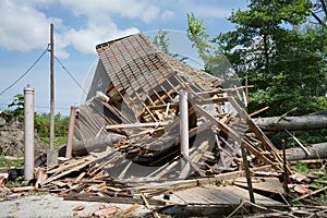 A house damaged by hurricane with fallen tree in front and on the house