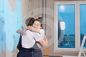 House decoration DIY renovation concept. Happy couple during repair in empty room of new home painting wall together