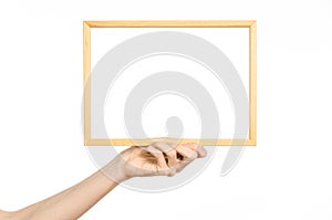 House decoration and Photo Frame topic: human hand holding a wooden picture frame isolated on a white background in studio