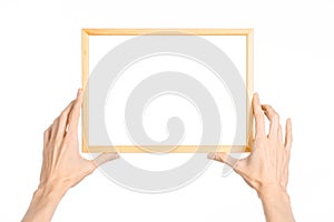 House decoration and Photo Frame topic: human hand holding a wooden picture frame isolated on a white background in the studio fir