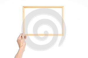 House decoration and Photo Frame topic: human hand holding a wooden picture frame isolated on a white background in the studio fir