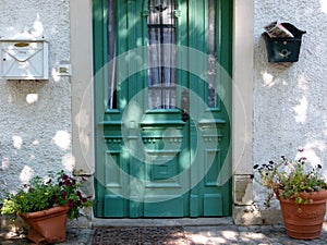 House entrance with green front door with 2 letter boxes and pots in terracotta