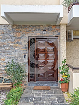 A house entrance solid wooden door on stone decorated wall and a flowerpot