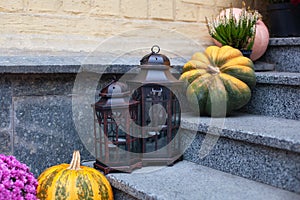 House entrance staircase decorated for autumn holidays, fall flowers and pumpkins. Cozy porch of the house with vintage lanterns i