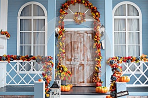 House entrance staircase decorated for autumn holidays, fall flowers and pumpkins. Cozy wooden porch of the house with pumpkins